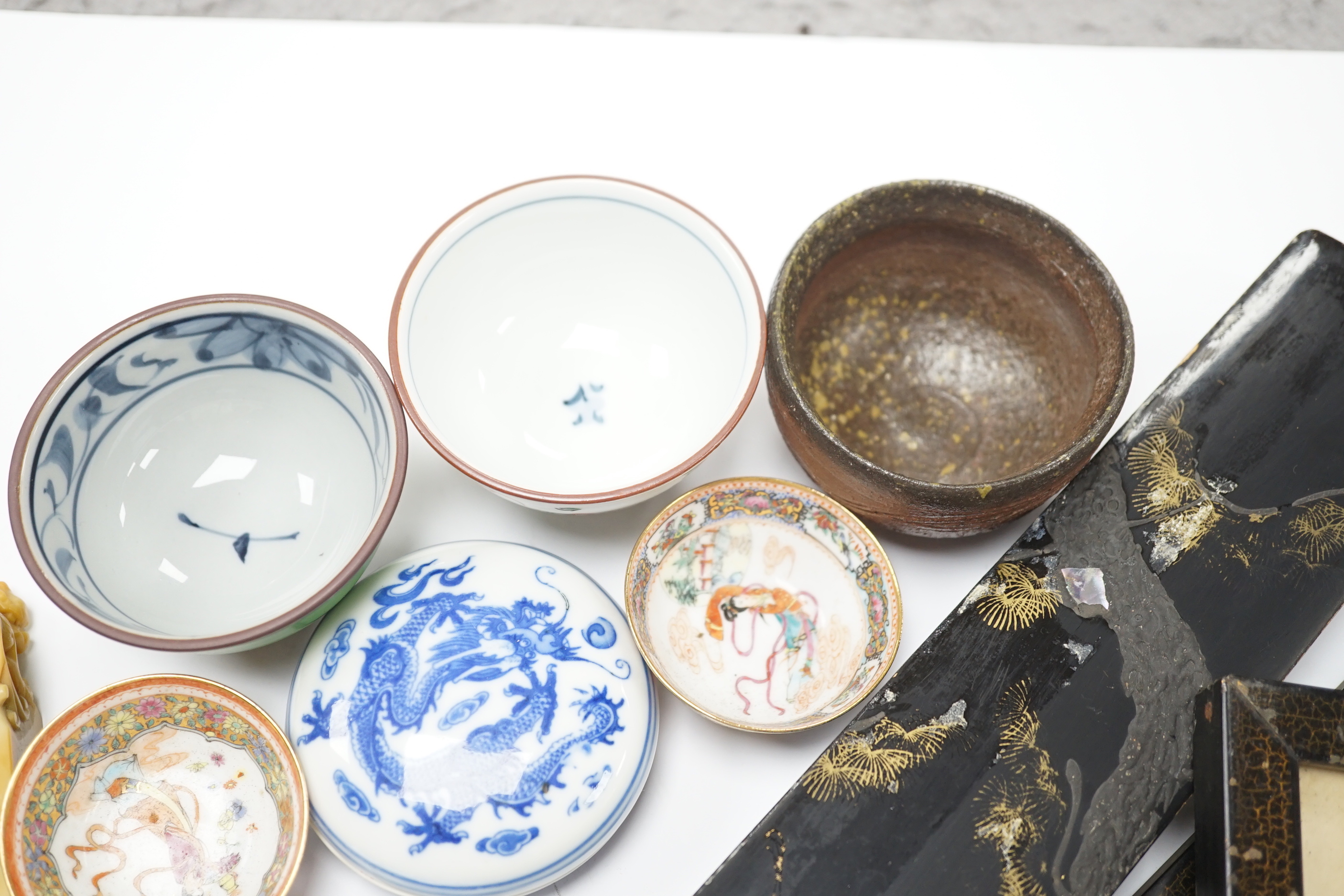 A group of Chinese and Japanese ceramics and works of art including two carved seals and tea bowls housed in a red lacquered box